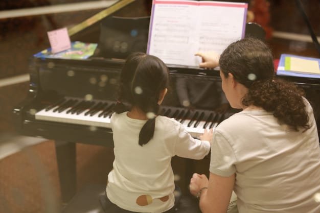 Child having a private tutor on how to play piano